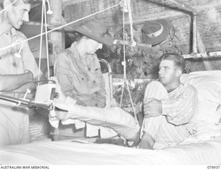 LAE, NEW GUINEA. 1945-03-27. LADY WAKEHURST (2), ACCOMPANIED BY SX1471 MAJOR N.P. WILSON, OFFICER- IN- CHARGE OF THE WARD (1), SPEAKS WITH VX12847 SAPPER G.W. MCKINNEY (3), DURING HER VISIT TO NO.3 ..