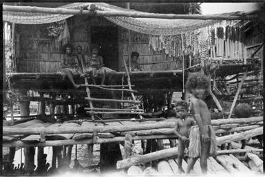 Four women sitting on verandah of marine house, Papua, ca. 1923 / Sarah Chinnery