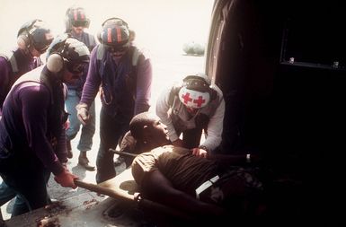 A corpsman checks on a wounded soldier who has just arrived by helicopter aboard the amphibious assault ship USS GUAM (LPH 9) during Operation URGENT FURY