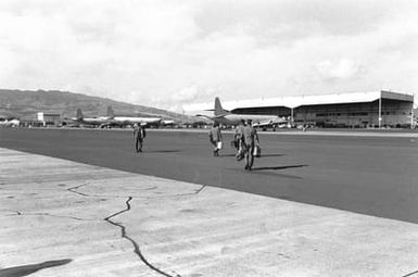 Members of Naval Air Reserve Patrol Squadron 64 (VP-64) walk to their P-3 Orion aircraft on the flight line