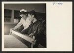 Pvt. Kenichi Kawakami is being shown how to manage a loom by the Occupational Therapist at Moore General Hospital at