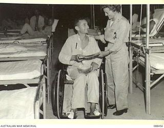 FINSCHHAFEN, NEW GUINEA. 1945-04-04. LEADING AIRCRAFTMAN S.S. GLUCK, 17 STORES UNIT RAAF, WITH LIEUTENANT M. HALTON, US ARMY NURSE, IN WARD 4, 237 STATION HOSPITAL