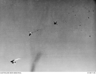 GONA, PAPUA. 11 DECEMBER 1942. ALLIED PLANES BOMB JAPANESE POSITIONS. ALLIED PLANE WHICH BLEW TO PIECES IN MID-AIR. TAIL AND FIN PORTIONS CAN BE SEEN FLOATING DOWN AMIDST THE WRECKAGE