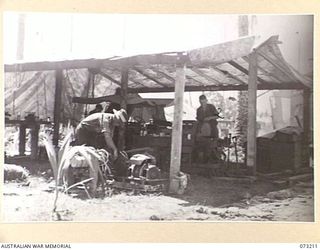 ALEXISHAFEN, NEW GUINEA. 1944-05-15. VX68698 DRIVER SIDNEY THOMAS CORRIE (1), AND QX26418 SERGEANT O C FREUDENBERG (2), ATTACHED TO THE 2/15TH FIELD AMBULANCE, AT WORK IN THE MECHANICAL REPAIR SHOP ..