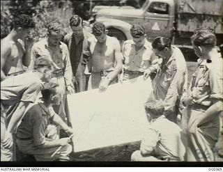 KIRIWINA, TROBRIAND ISLANDS, PAPUA. C. 1943-11. CREWS OF NO. 22 (BOSTON) SQUADRON RAAF, BEING BRIEFED. LEFT TO RIGHT: SERGEANT (SGT) G. DIXON, ST KILDA, VIC; FLIGHT LIEUTENANT DRISCOLL, STAWELL, ..