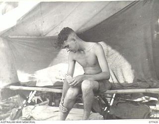 MALMAL MISSION, JACQUINOT BAY, NEW BRITAIN. 1944-11-30. SERGEANT R.M. BARRETT, HEADQUARTERS, 5TH DIVISION, APPLYING MOSQUITO REPELLANT