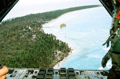 SSGT Tony Thompson, loadmaster with the 21st Tactical Airlift Squadron, watches as a Christmas Drop container floats toward its destination. The annual airdrop is a humanitarian effort providing aid to needy islanders throughout Micronesia during the holiday season