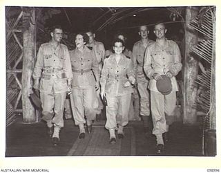 LAE, NEW GUINEA. 1945-11-25. A PARTY OF AUSTRALIAN ARMY NURSING SERVICE SISTERS AND ARMY OFFICERS ENTERING THE AUSTRALIAN ARMY CANTEENS SERVICE OFFICERS' CLUB WHICH IS SITUATED ON THE BANKS OF THE ..