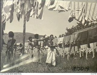 PORT MORESBY, PAPUA. C. 1944. PAPUAN NATIVES EMPLOYED BY THE RAAF HANG OUT WASHING ON CLOTHES LINES