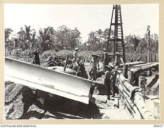 ANAMO AREA, NEW GUINEA. 1944-11-24. A BULLDOZER, WATCHED BY MEMBERS OF THE 2/2 FIELD COMPANY, ROYAL AUSTRALIAN ENGINEERS, PUSHES UP EARTHWORKS TO THE EASTERN APPROACHES OF A BRIDGE ACROSS AN ..
