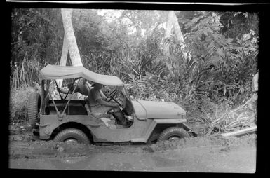 RNZAF airmen trying to move a jeep that has become stuck in mud, Guadalcanal, Solomon Islands