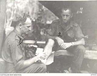 MALMAL MISSION, JACQUINOT BAY, NEW BRITAIN. 1944-11-30. CORPORAL H. CAROTHERS, MEDICAL ORDERLY (2) HEADQUARTERS, 5TH DIVISION, TREATING A DERMATITIS INFECTION ON THE LEG OF GUNNER C. HAMMER (1) AT ..