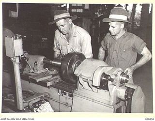 RABAUL, NEW BRITAIN. 1945-11-08. CORPORAL H.D. WORTHINGTON (1) AND SAPPER A.R. WATSON (2) TURNING A SPINDLE ON A LATHE IN THE WORKSHOP, 51 AND 55 ORDNANCE FIELD PARK