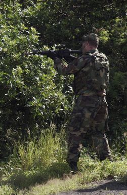 During an exercise, US Air Force (USAF) AIRMAN First Class (A1C) John Dowd fires his Colt 5.56mm M16A2 Assault Rifle at the enemy as he evades through the woods at Bellows Air Force Station (AFS), Hawaii (HI)