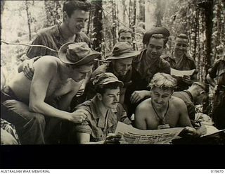 Goodview Junction, New Guinea. c. 1943-09. Australian troops within half a mile of the Japanese front line, being watched by American colleagues, as they prepare to vote in a Federal election. ..
