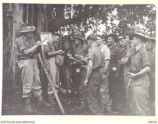 RABAUL, NEW BRITAIN. 1945-11-06. THE BOOKMAKER AND HIS CLERK ON THE JOB AT HEADQUARTERS 11 DIVISION, TAKING BETS BEFORE THE START OF THE MELBOURNE CUP