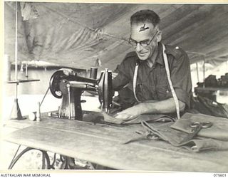 MARKHAM VALLEY, NEW GUINEA. 1944-08-28. V39481 SERGEANT J.W. LUNN, REGIMENTAL TAILOR, 4TH FIELD REGIMENT REPAIRING UNIFORMS