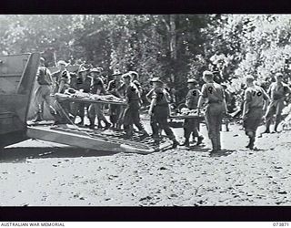 KARKAR ISLAND, NEW GUINEA. 1944-06-16. MALARIA STRETCHER CASES BEING CARRIED ONTO BARGES BY MEMBERS OF AN ADVANCED DRESSING STATION OF 2/15TH FIELD AMBULANCE OPERATING NEAR ALEXISHAFEN WITH ..
