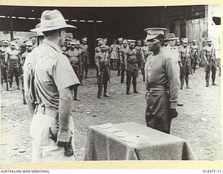 1943-03-03. AN ADMINISTRATION OFFICER, MAJOR VERTIGAN D.O. TRANSLATES INTO PIDGIN THE G.O.C.'S WORDS OF PRAISE TO A NATIVE MEDAL WINNER AT WAU AERODROME, WHERE FOUR MEMBERS OF THE NATIVE ..