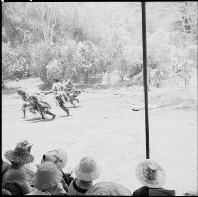 Fijian men, dressed in traditional costumes, pulling logs away from the fire, Fiji, 1966 / Michael Terry