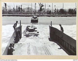 TOROKINA AREA, BOUGAINVILLE, 1945-08-06. M24 GENERAL CHAFFEE LIGHT TANKS PARTICIPATING IN WAR OFFICE TRIALS, MOVING ASHORE FROM AN AUSTRALIAN LANDING CRAFT. THE SECOND TANK BECOMES PARTLY SUBMERGED ..