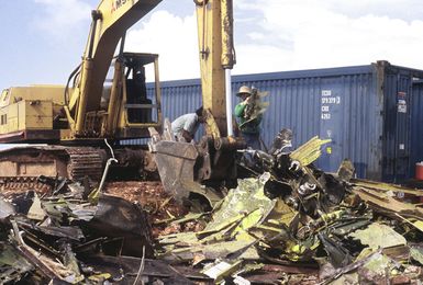 A ditch-digging machine lifts the scrap from a B-52D aircraft, to load it onto a modular freight container. Three of the strategic bombers are being discarded in accordance with the SALT II treaty between the United States and the Soviet Union