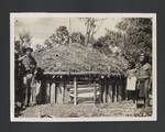 People standing in front of thatched roof building, Upper Ramu, Papua New Guinea, c1949