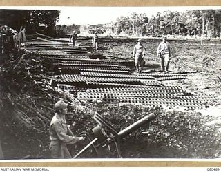FINSCHHAFEN AREA, NEW GUINEA. 1943-11-09. SHEET METAL STRIPS STACKED AT THE SIDE OF THE NEW AIR-STRIP IN READINESS FOR LAYING BY THE ENGINEERS OF THE 808TH UNITED STATES ENGINEER AVIATION BATTALION ..