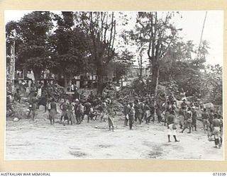 MADANG, NEW GUINEA. 1944-05-18. NATIVES WORKING UNDER THE CONTROL OF THE AUSTRALIAN NEW GUINEA ADMINISTRATIVE UNIT GATHERED AT THE WATERFRONT OFFICE AT THE END OF A DAY SPENT IN CLEANING THE AREA. ..