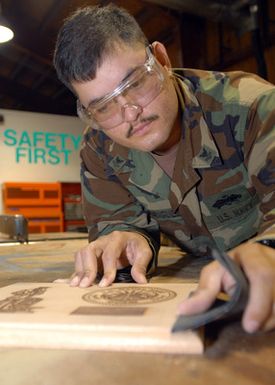 US Navy PETTY Officer 2nd Class Rodney Rodriguez, a Seabee assigned to Naval Facilities Engineering Command Marianas, sands the edge on a mahogany plaque at Naval Base Guam. The plaque is being prepared for an award ceremony recognizing NB Guam's top Sailors. (U.S. Navy photo by Mass Communication SPECIALIST 2nd Class John F. Looney) (Released)