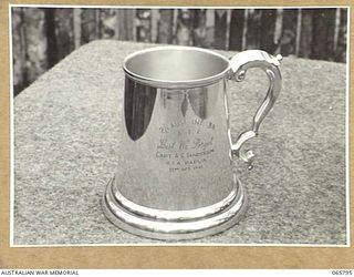 WONDECLA, QLD. 1944-04-15. THE SILVER MEMORIAL MUG DEDICATED TO NX7567 CAPTAIN A.G. SANDERSON OF THE 2/1ST INFANTRY BATTALION WHO WAS KILLED IN ACTION IN PAPUA ON THE 23 OCTOBER 1942. MEMBERS OF ..