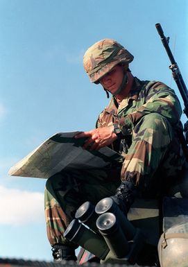 Lieutenant (LT) Micheal Simek US Army (USA), 1ST Battalion, 17th Infantry Division sit atop a Light Armored Vehicle (LAV-25) as he reads a map in preparation for the Non-combatant Evacuation Operation (NEO) at Orote Point, Guam during Exercise TANDEM THRUST '99