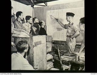 MOMOTE, LOS NEGROS ISLAND, ADMIRALTY ISLANDS. C. 1944-04. OFFICERS AND NON COMMISSIONED OFFICER PILOTS OF NO. 76 (KITTYHAWK) SQUADRON RAAF BEING BRIEFED BY THE COMMANDING OFFICER, SQUADRON LEADER ..