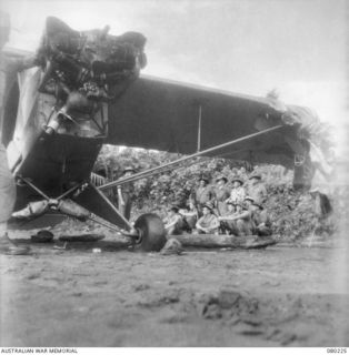 DUGUMUR, NEW GUINEA. 1944-07. NX120317 CAPTAIN E.L. BYRNE (1), INSTRUCTING MEMBERS OF 242ND SUPPLY DEPOT PLATOON, AUSTRALIAN ARMY SERVICE CORPS NEAR A PIPER CUB AIRCRAFT. THE AIRCRAFT CRASHED ..