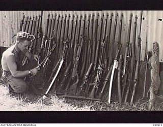 KAIAPIT, NEW GUINEA. 1943-09-26. VX64661 CORPORAL W. D. BIRD, ARMOURER OF THE 2/6TH AUSTRALIAN INDEPENDENT COMPANY WORKING ON CAPTURED JAPANESE ORDNANCE, WHICH CONSISTS OF RIFLES, LIGHT MACHINE ..