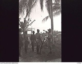 WAIWAI, NEW GUINEA. 1942-11. CAPTAIN T. GRAHAMSLAW OF ANGAU POINTS OUT TO SERGEANT MAJOR KATUE, OF THE PAPUAN INFANTRY BATTALION, AND NATIVE POLICE THE GENERAL DIRECTION OF ORO BAY, NEW GUINEA, ..