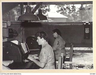 LAE, NEW GUINEA, 1945-05-16. SIGNALWOMAN B. BURGESS (1) AND SIGNALWOMAN L.A. WILLIAMS (2), AUSTRALIAN WOMEN'S ARMY SERVICE TELEPRINTER OPERATORS AT THE SIGNAL OFFICE, HEADQUARTERS LAE BASE ..