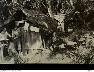 Guadagasal, New Guinea. 1943-07-21. A and Q huts of Headquarters, 17th Australian Infantry Brigade. Shown, from the left, are, VX5902 Corporal F. Milroy, SX9708 Sergeant F.D. Ruse, NX28051 Captain ..