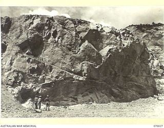 NINE MILE QUARRY AREA, PORT MORESBY, NEW GUINEA. 1944-01-22. THREE MEMBERS OF THE 12TH COMMANDER ROYAL ENGINEERS, (WORKS), (A.I.F.), AT A SECTION OF THE QUARRY FACE AT NINE MILE QUARRY BEFORE IT IS ..