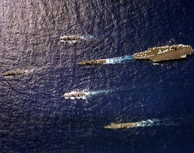 An overhead view of the nuclear-powered aircraft carrier USS CARL VINSON (CVN-70) underway near Hawaii with its battle group. Top to bottom are the frigate USS COOK (FF-1083), the destroyer USS HEWITT (DD-966), the frigate USS BARBEY (FF-1088), the nuclear-powered guided missile cruiser USS TEXAS (CGN-39) and, leading the formation, the guided missile frigate USS SIDES (FFG-14)