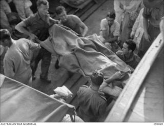 LALUM, BOUGAINVILLE, 1945-06-12. PATIENTS FROM 19 FIELD AMBULANCE MAIN DRESSING STATION BEING TRANSFERRED FROM BARGE TO THE HOSPITAL SHIP STRADBROKE. THE MEN WERE WOUNDED DURING THE PORTON ..