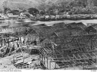 1943-06-09. NEW GUINEA. THIS NATIVE VILLAGE, HANUABADA, MEANING "BIG VILLAGE," HAD A PRE- WAR POPULATION OF 2,700 ROOFED WITH CUNAI GRASS OR BIRI PALMS, THE HUTS HAVE TO BE REROOFED AT THREE YEAR ..