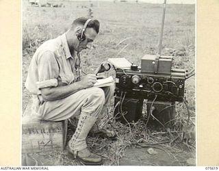 MARKHAM VALLEY, NEW GUINEA. 1944-08-28. VX118259 LIEUTENANT L.W. MOUNSEY, 4TH FIELD REGIMENT, RECEIVING FIRING ORDERS FROM THE OBSERVATION POST DURING A UNIT PRACTICE SHOOT