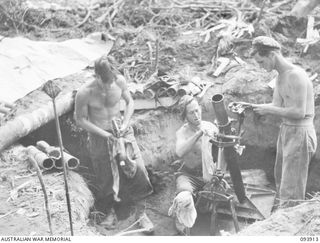 BOUGAINVILLE, 1945-07-12. A MORTAR CREW OF D COMPANY, 15 INFANTRY BATTALION, CLEANING THEIR WEAPONS WHILE WAITING FOR A REPORT ON ENEMY POSITIONS FROM A PATROL. THE MEN ARE IN A WEAPON PIT IN THE ..