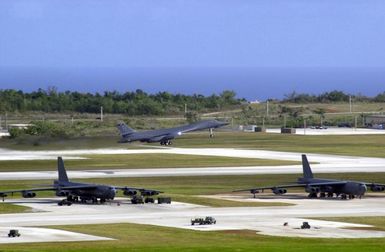 Near several parked US Air Force (USAF) B-52 Stratofortress bombers, a B-1B Lancer Bomber, deployed from Dyess Air Force Base (AFB), Texas, takes off from Andersen AFB, Guam, in support of the 7th Air Expeditionary Wing's mission