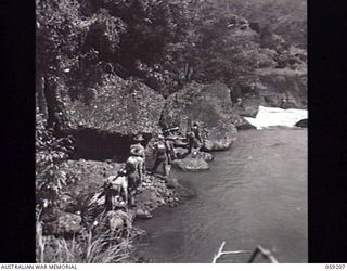 LALOKI VALLEY, NEW GUINEA. 1943-11-05. A PATROL OF THE NEW GUINEA FORCE TRAINING SCHOOL (JUNGLE WING) PASSING A ROCKY EDGE OF A BASIN NEARING THE ROUNA FALLS