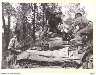 BOUGAINVILLE. 1945-05-21. TROOPS OF 24 INFANTRY BATTALION LOADING 3-INCH MORTAR AND BOMBS ONTO THE REAR OF A MATILDA TANK FOR TRANSPORT FORWARD TO EGAN'S RIDGE ALONG THE BUIN ROAD. PATROLS MOVING ..