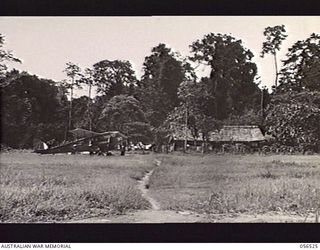 REINHOLD HIGHWAY, NEW GUINEA, 1943-09-04. HEADQUARTERS BUILDING, BULLDOG BASE AREA, SHOWING DRAGON RAPIDE AIRCRAFT ON THE AIRSTRIP AT THE LEFT FOREGROUND