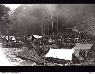 REINHOLD HIGHWAY, NEW GUINEA. 1943-08-25. FIRST CONVOY TO TRAVERSE THE NEW 68 MILE HIGHWAY, PAUSE AT FOX'S SADDLE TO GREET THE HIGHWAY BUILDERS, TROOPS OF HEADQUARTERS, ROYAL AUSTRALIAN ENGINEERS, ..