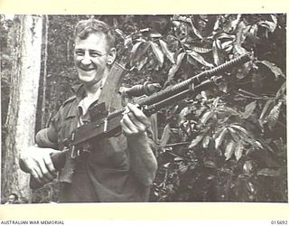 Private (Pte) William (Bill) Plunkett, of Geelong, Vic, with a Japanese light machine gun found after the Australians had driven the enemy from the ridge. The Japanese weapon closely resembles a ..